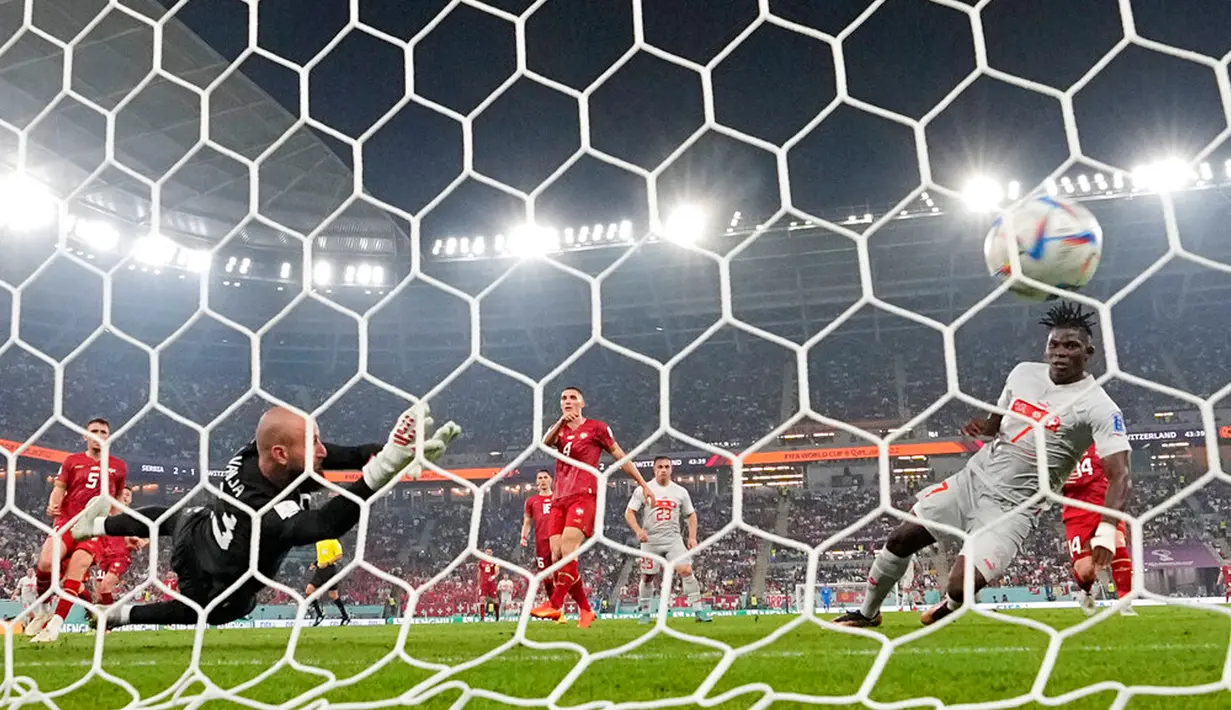 Pemain Swiss Breel Embolo mencetak gol ke gawang Serbia yang dijaga Vanja Milinkovic-Savic pada pertandingan sepak bola Grup G Piala Dunia 2022 di Stadion 974, Doha, Qatar, 2 Desember 2022. Swiss melaju ke babak 16 besar Piala Dunia 2022 setelah mengalahkan Serbia dengan skor 3-2. (AP Photo/Martin Meissner)