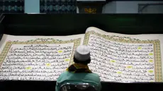 Umat Islam membaca Al-Quran raksasa yang ditulis tangan, berukuran 142 x 210 cm, selama bulan suci Ramadan, di Masjid Baiturrahman, Banyuwangi, Jawa Timur, pada 26 Maret 2024. (Noly Falah/AFP)