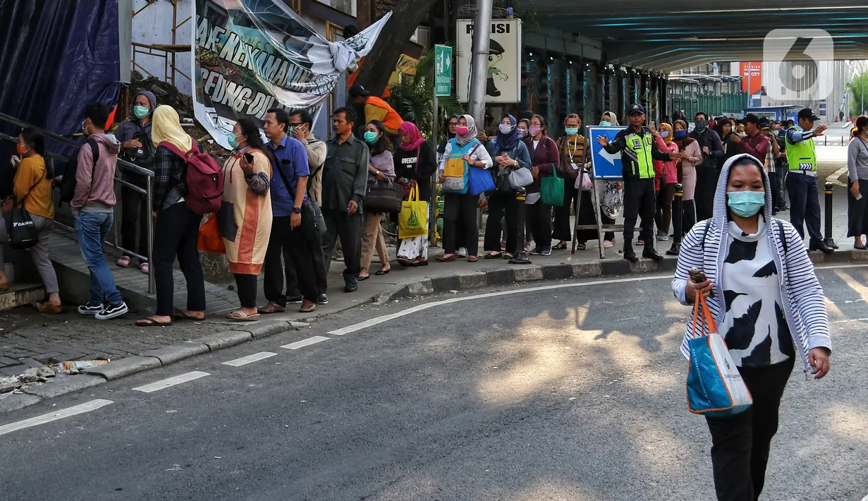 Antrean calon penumpang KRL Commuter Line untuk memasuki Stasiun Sudirman, Jakarta, Selasa (17/3/2020. Terjadi antrean akibat PT Kereta Commuter Indonesia (KCI) memberlakukan kebijakan pengecekan suhu tubuh bagi penumpang KRL mengantisipasi penyebaran virus corona Covid-19.\ (Liputan6.com/Johan Tall