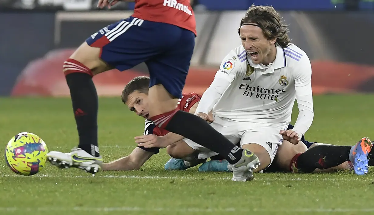 Gelandang Real Madrid, Luka Modric dilanggar saat bertanding melawan Osasuna pada pertandingan lanjutan La Liga Spanyol di stadion El Sadar di Pamplona, Spanyol, Minggu (19/2/2023). Pasukan Carlo Ancelotti masih berada di posisi kedua dan tertinggal lima angka dari Barcelona di puncak klasemen. (AP Photo/Alvaro Barrientos)