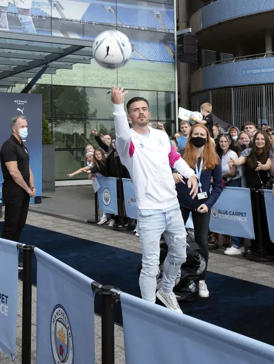 Pemain baru Manchester City, Jack Grealish, melemparkan bola kepada para penngemar saat diperkenalkan di Stadion Etihad, Senin (9/8/2021). Jack Grealish akan mengenakan kostum nomor 10, yang sebelumnya menjadi milik Sergio Aguero. (AP Photo/Jon Super)