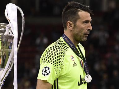 Kiper Juventus, Gianluigi Buffon, tampak sedih ketika melewati piala Liga Champions di Stadion Millennium, Sabtu (3/6/2017). Juventus kalah 1-4 dari Real Madrid. (AFP/Javier Soriano)