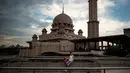 Gambar yang diambil pada 22 November 2017, memperlihatkan seorang turis berpose di depan masjid berwarna pink di kawasan Putrajaya, Malaysia. Masjid Putra ini terdiri dari 4 lantai yang dilengkapi dengan lift. (MANAN VATSYAYANA/AFP)