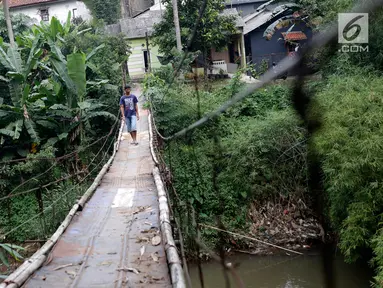 Warga melintasi jembatan penyeberangan buatan warga di kawasan Lenteng Agung, Jakarta, Rabu (24/5). Meskipun kondisinya memprihatinkan, warga setempat tetap menggunakan jembatan tersebut. (Liputan6.com/Immanuel Antonius)