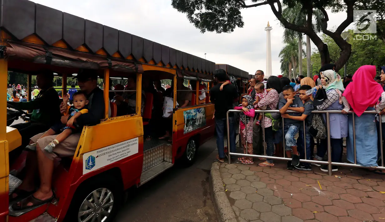 Sejumlah pengunjung mengantre untuk menaiki kereta wisata di halaman Monumen Nasional, Jakarta, Rabu (27/6). Libur ketiga Lebaran dimanfaatkan warga untuk bekunjung ke lokasi wisata bersama keluarga. (Liputan6.com/Johan Tallo)