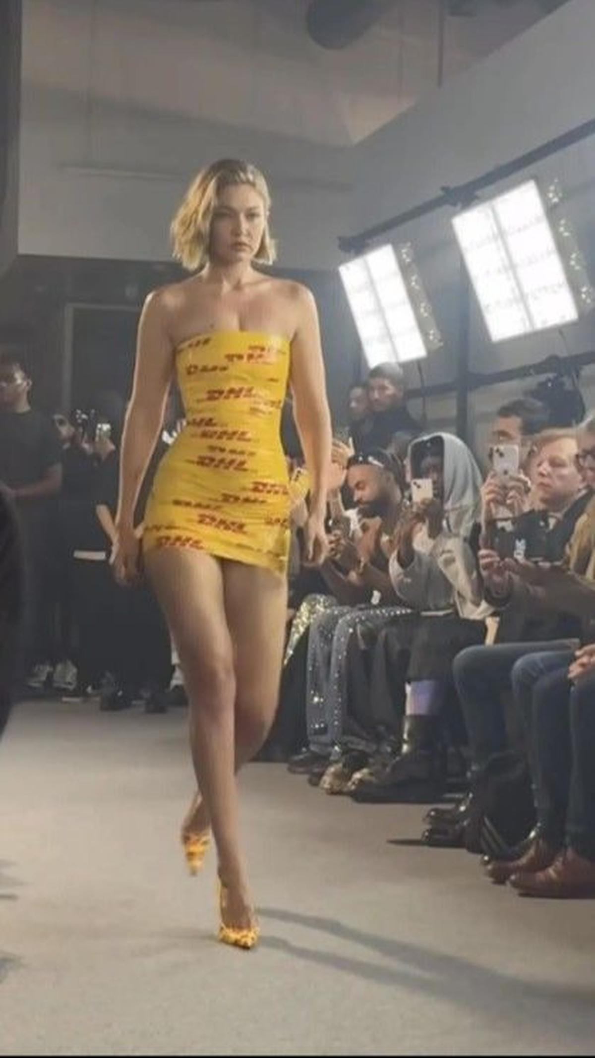 Menariknya, Gigi Hadid memilih untuk tidak mengenakan pakaian mewah, melainkan mini dress unik yang terbuat dari selotip kuning dengan tulisan "DHL" merah, menjadikannya tampil sangat eksentrik.<br><br>