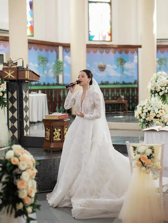 Rambutnya ditata sleek look; dibelah tengah dan diberi veil putih yang serasi dengan gaun pengantinnya. [Foto: Instagram/anggimarito]