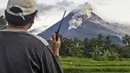 Seorang relawan menggunakan walkie talkie-nya saat memantau Gunung Merapi saat erupsi di Sleman (27/1/2021). Sekitar 150 warga di lereng barat daya Gunung Merapi di Kabupaten Sleman, DIY, mengungsi dari rumah, Rabu (27/1/2021) sore. (AP Photo/Slamet Riyadi)