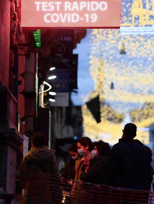 Orang-orang menunggu di luar apotek untuk dites Covid-19 sebelum Natal, di Roma, Italia pada Kamis (23/12/2021). Pemerintah Italia telah mewajibkan kembali penggunaan masker di luar ruangan untuk menahan peningkatan kasus Covid-19 yang didorong oleh varian Omicron. (Filippo MONTEFORTE/AFP)