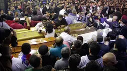 Umat Kristen Mesir memberikan penghormatan terakhir di samping peti jenazah korban serangan bom di Gereja Koptik St. George, Kota Tanta, utara Kairo, Minggu (9/4). Sebanyak 44 orang tewas dalam serangan bom di dua gereja koptik Mesir. (STRINGER/AFP)