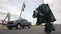 Kendaraan melintasi lampu lalu lintas yang tergantung di kabel setelah terjangan Badai Ida di LaPlace, Louisiana, Senin (30/8/2021). Badai Ida ini sebagai salah satu badai paling kuat yang pernah melanda Amerika Serikat. (AP Photo/Steve Helber)