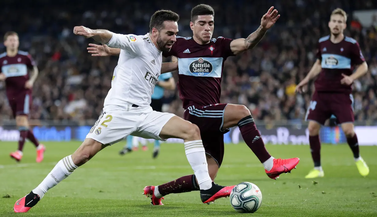 Bek Real Madrid, Dani Carvajal berebut bola dengan pemain Celta Vigo, Gabriel Fernandez selama pertandingan lanjutan La Liga Spanyol di stadion Santiago Bernabeu di Madrid, Spanyol, Minggu, (16/2/2020). Madrid bermain imbang 2-2 atas Celta Vigo.  (AP Photo/Manu Fernandez)