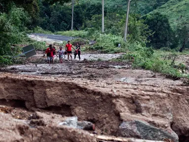 Orang-orang berjalan di sepanjang jalan yang hancur dan hanyut di komunitas Kilometro 42, dekat Acapulco, Negara Bagian Guerrero, Meksiko, setelah Badai Otis, pada 25 Oktober 2023. (RODRIGO OROPEZA/AFP)