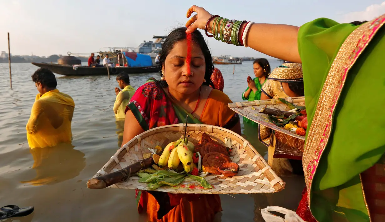 Seorang wanita Hindu diolesi bubuk vermilion di dahinya saat mengikuti festival keagamaan Chhat Puja di Kolkata, India (6/11). Dalam ritual menyembah Dewa Matahari ini mereka meminta kesejahteraan, dan kemakmuran. (Reuters/Rupak De Chowdhuri)