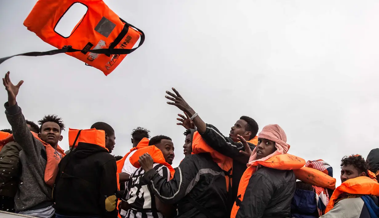Pengungsi dan migran menerima pelampung saat diselamatkan oleh LSM Spanyol Proactiva Open Arms di atas sebuah kapal karet, 60 mil sebelah utara Al -Khum, Libya (18/2). Para pengungsi dan migran ini meninggalkan Libya untuk ke Eropa. (AP Photo/Olmo Calvo)