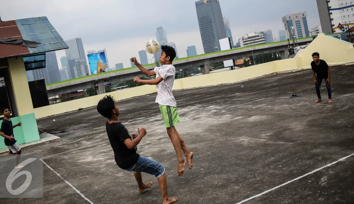 Seorang remaja menyundul bola saat bermain futsal di atas gedung di Pasar Mampang, Jakarta, Rabu (12/7).  Tempat bermain untuk anak-anak yang tidak berbayar masih sangat kurang di DKI Jakarta. (Liputan6.com/Faizal Fanani)