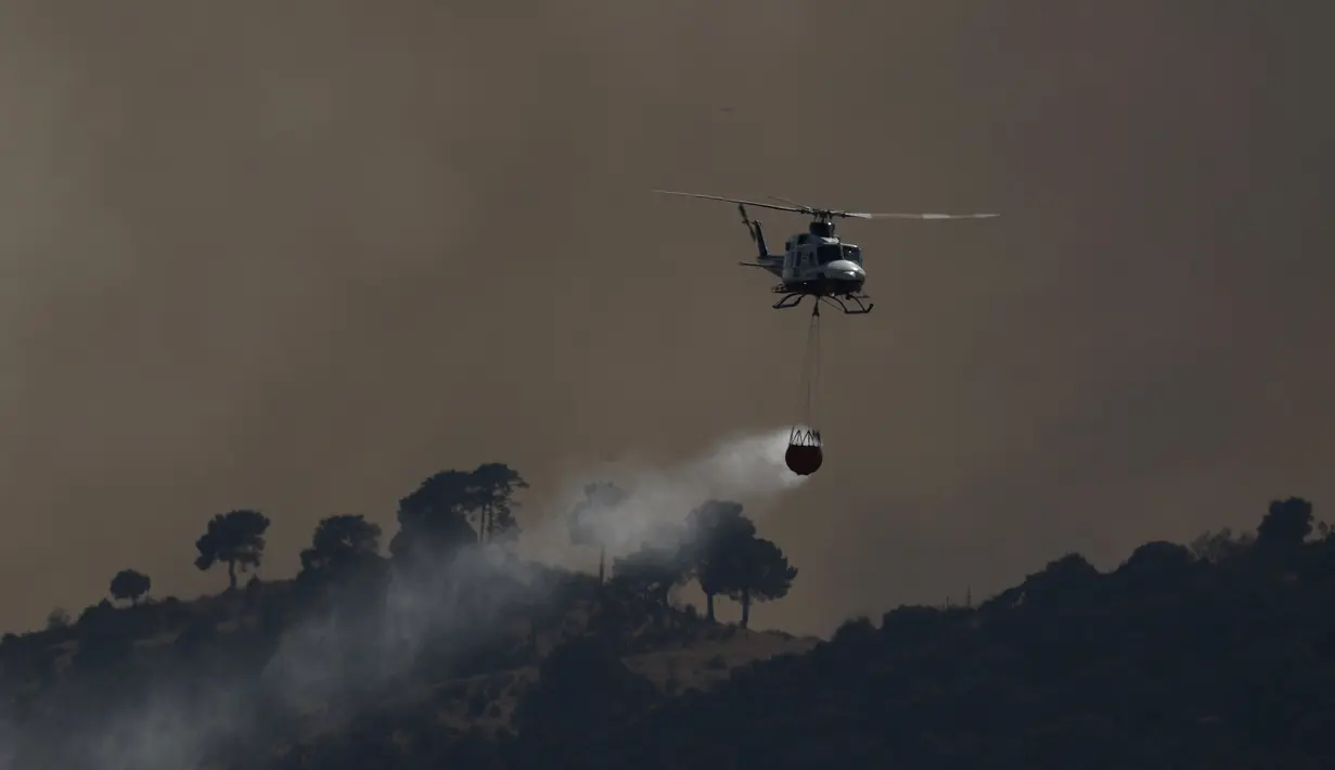 Sebuah helikopter pemadam kebakaran menjatuhkan air ke kebakaran hutan di dekat Robledo de Chavela, sekitar 60 kilometer sebelah barat Madrid, Senin, 27 Juli 2026.(AFP/  Oscar DeL Pozo)