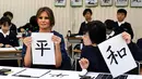 Melania Trump (kiri) dan Istri PM Jepang, Akie Abe menunjukkan huruf kanji yang berarti "Damai" saat menghadiri kelas kaligrafi di sekolah dasar Kyobashi Tsukiji, Tokyo (6/11). (AFP Photo/Pool/Toshifumi Kitamura)