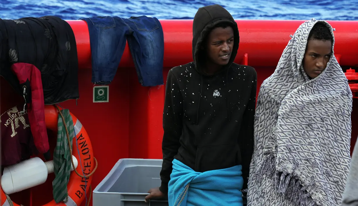 Dua migran berdiri di atas geladak kapal penjaga pantai LSM Spanyol Open Arms setelah mereka diselamatkan dari perairan terbuka selama operasi penyelamatan di zona perairan internasional di Laut Mediterania, Rabu, 21 September 2022. Lebih dari empat ratus migran dari Mesir, Suriah, Pakistan, Bangladesh, Eritrea, Sudan, Ethiopia, Somalia, diselamatkan oleh anggota awak LSM Open Arms. (AP/Petros Karadjias)