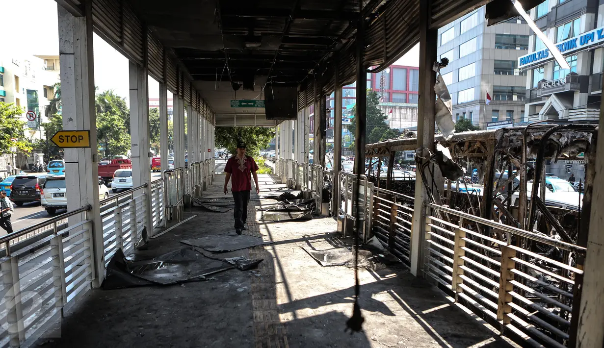 Warga berjalan di halte UI Salemba yang ikut terbakar bersama dengan Bus gandeng Transjakarta koridor V Ancol - Kampung Melayu pagi tadi, Jakarta, Jumat (7/3/2015). Akibat kebakaran tersebut, Halte UI Salemba rusak ringan. (Liputan6.com/Faizal Fanani)