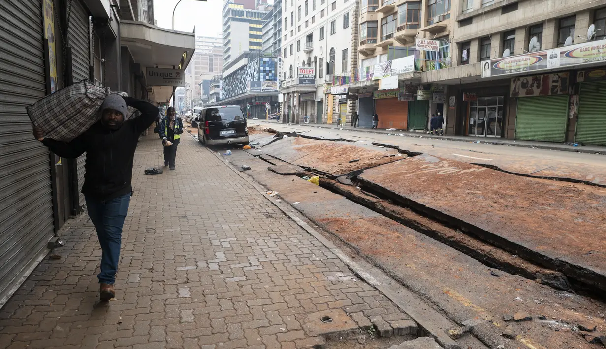 Sebuah ledakan yang diduga berasal dari gas bawah tanah merobek jalan dan menjungkirbalikkan kendaraan di jantung kota terbesar di Afrika Selatan. (Luca Sola / AFP)
