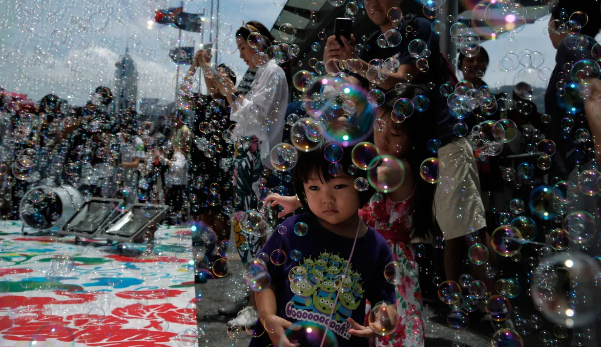 Seorang anak perempuan bermain gelembung selama pertunjukan seni Bubble Up yang dibuat oleh seniman asal Jepang, Shinji Ohmaki, di Hong Kong, 2 Agustus 2017. (AP Photo/Kin Cheung)
