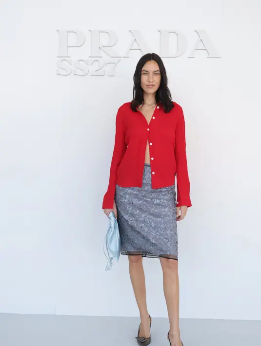 Alexa Chung tampil dengan kemeja merah sebagai paduan rok payet abu-abu metalik, clutch biru muda, dan heels metalik runcing [dok. Prada)