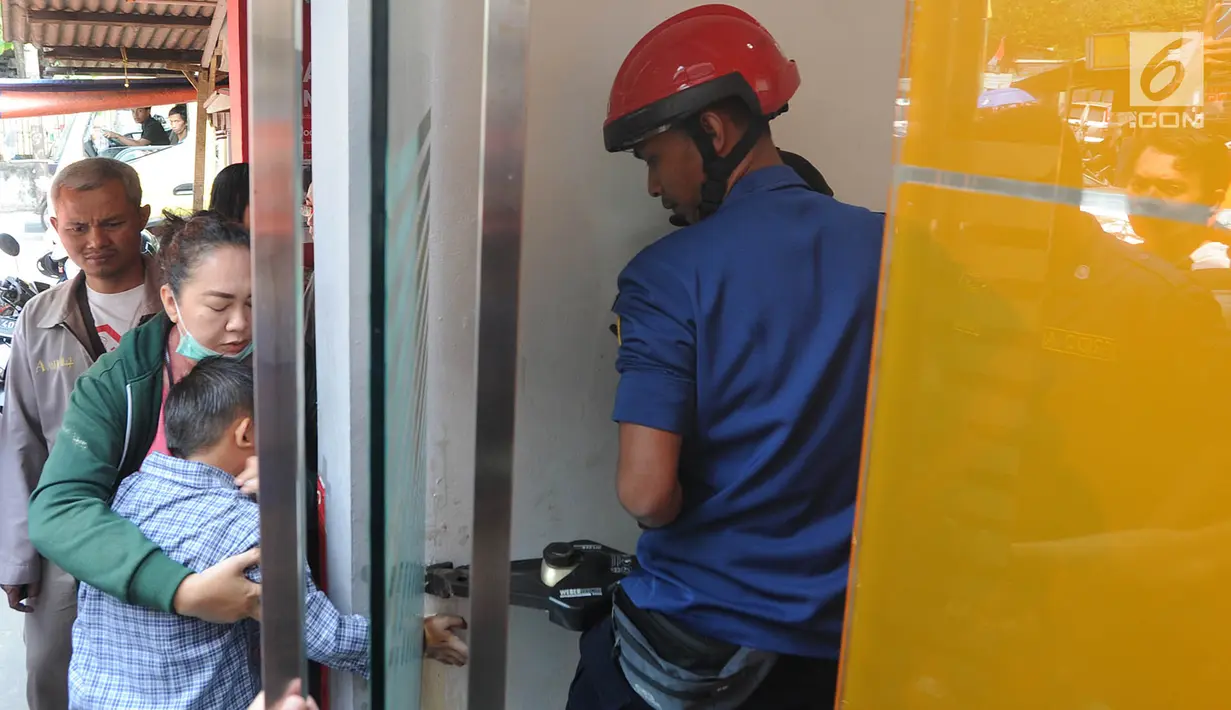 Petugas Damkar dari Pos Pesanggrahan berusaha menyelamatkan tangan murid TK, Fathur yang terjepit kaca pintu ATM Bank BNI di Jalan M. Saidi, pesanggrahan, Jakarta Selatan, Senin (5/8/2019). Fathur terjepit pintu saat ibunya mengambil uang di ATM tersebut. (merdeka.com/Arie Basuki)