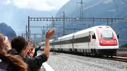 Pengunjung melambaikan tangan ke arah kereta api yang melintasi terowongan Gotthard di kota Erstfeld, Swiss, Rabu (1/6). Swiss resmi membuka terowongan kereta api terpanjang, yang membentang sepanjang 57 km di bawah Pegunungan Alpen. (REUTERS/SRG/Pool)