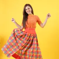 Ibu dua anak tersebut memakai atasan kaus knit dengan kerah tinggi nuansa retro yang dipasangkan dengan maxi skirt bermotif kotak-kotak dengan pinggang tinggi beraksen korset. (Foto: Fimela.com/Bambang E.Ros)