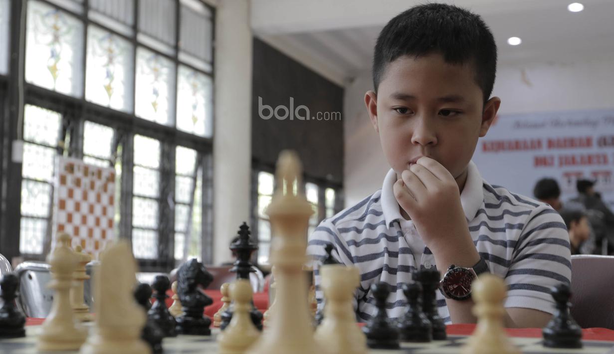 Seorang pecatur cilik tampak serius saat mengikuti kejuaraan catur daerah tingkat provinsi DKI Jakarta di Wisma Catur KONI Jakarta, Minggu (9/7/2017). Kejuaraan ini diikuti oleh 140 anak. (Bola.com/M Iqbal Ichsan)