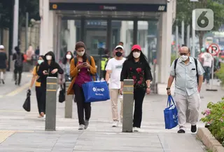 Sejumlah pekerja berjalan saat jam pulang kerja di Jalan Jenderal Sudirman, Jakarta, Rabu (3/11/2021). Salah satu aturan kerja pada sektor non esensial diizinkan bekerja dari kantor atau 'work from office' (WFO) 75 persen dan sektor esensial 100 persen. (Liputan6.com/Herman Zakharia)