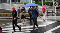 Pejalan kaki melintas menggunakan payung saat hujan mengguyur kawasan Jakarta, Senin (3/2/2020). Diperkirakan sejumlah wilayah berpotensi diguyur hujan dengan intensitas lebat hingga disertai dengan angin kencang, kilat/petir hingga Rabu (5/2/2020) mendatang. (Liputan6.com/Angga Yuniar)