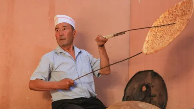 Rishit Himit membuat roti naan di toko miliknya di Kota Kuqa, Daerah Otonom Uighur Xinjiang, China barat laut, pada 22 Juli 2025. (Dok. Xinhua/Wang Fei)