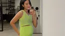Memamerkan baby bump-nya lewat mirror selfie, Alika tampak chic mengenakan setelan knit ketat warna hijau neon.  (Instagram/alikaislamadina).