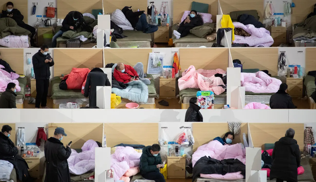 Aktivitas pasien dengan gejala ringan virus corona COVID-19 yang beristirahat pada malam hari di stadion olahraga yang diubah menjadi rumah sakit darurat di Wuhan, China pada 18 Februari 2020. Jumlah korban virus corona hingga Kamis (20/2) kembali meningkat menjadi 2.120 orang. (STR/AFP)