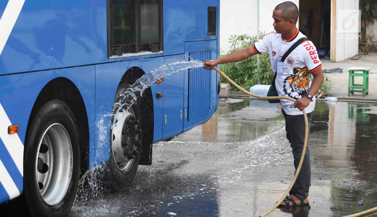 Suporter Persija Jakarta mencuci bus transjakarta di kantor PT Transjakarta, Jakarta, Kamis (13/12). Hal tersebut dilakukan bentuk tanggung jawab atas aksi vandalisme oknum suporter saat Persija meraih Juara Liga 1 2018. (Liputan6.com/Immanuel Antonius)