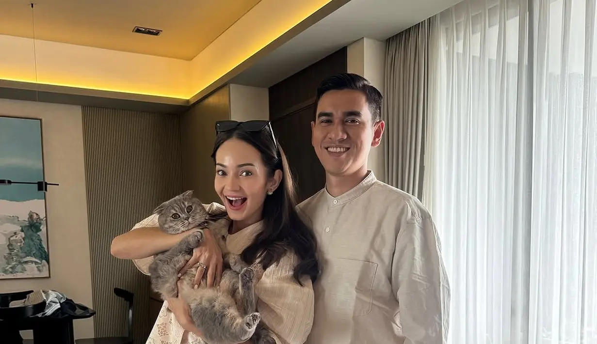 Enzy Storia tampil semi kasual kenakan kemeja soft pink dengan detail lace di bagian depan. Dipadu dengan celana satin dan kacamata hitam [@enzystoria]