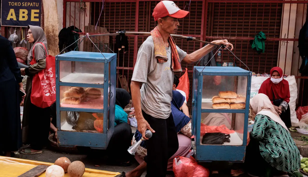 Seorang pedagang makanan kaki lima berjalan di sebuah pasar, Bogor, Jawa Barat pada 13 Februari 2025. (Yasuyoshi CHIBA/AFP)