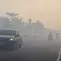 Para pengendara bermotor menyalakan lampu depan kendaraan saat melintasi jalan yang diselimuti kabut asap di Kota Palangka Raya, Kalimantan Tengah, Kamis, 20 Agustus 2026. (AFP/ Reina)