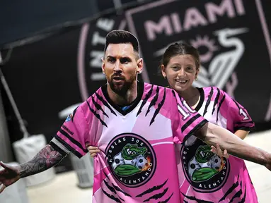 Seorang gadis membawa potongan karton berbentuk pemain baru Inter Miami, Lione Messi saat menunggu di luar Stadion DRV Pink, Miami, 11 Juli 2023. Transfer Messi menjadi paling menggemparkan pada musim panas 2023/2024. La Pulga memilih hengkang dari PSG menuju Inter Miami. Klub milik legenda sepak bola Inggris, David Beckham tersebut diketahui rela merogoh kocek 35 juta euro untuk mendatangkan sang bintang Argentina tersebut. (AP Photo/Rebecca Blackwell)