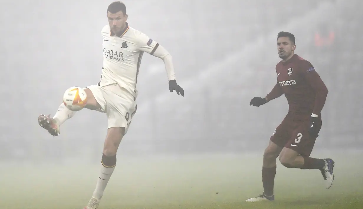 Penyerang AS Roma, Edin Dzeko mengontrol bola dari kawalan pemain CFR Cluj, Andrei Burca selama pertandingan grup A Liga Europa di Cluj-Napoca, Rumania (26/11/2020). AS Roma menang 2-0 atas CFR Cluj. (AFP/Alex Nicodim)
