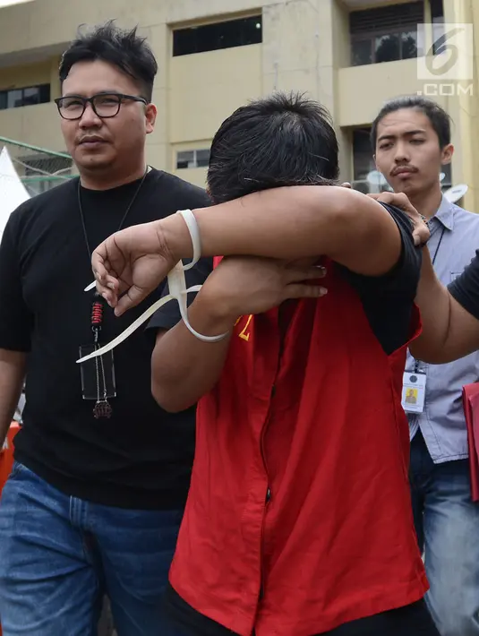 Tersangka berinisial MIK penyebar hoax surat suara tercoblos menutupi wajahnya saat digiring petugas di Polda Metro Jaya, Jakarta, Jumat (11/1). MIK ditangkap sekitar pukul 22.30 WIB, pada 6 Januari. (Merdeka.com/Imam Buhori)