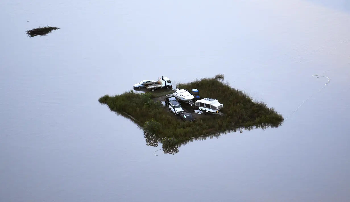 Kendaraan diparkir di sebidang kecil dataran tinggi di air banjir di daerah Windsor di barat laut Sydney, Australia, Rabu (24/3/2021).  Sekitar 18.000 penduduk negara bagian terpadat di Australia telah meninggalkan rumah mereka sejak pekan lalu, dengan peringatan banjir dapat berlanjut hingga April.