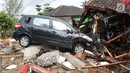 Dua unit mobil tertimbun reruntuhan rumah yang rusak setelah tsunami menerjang kawasan Anyer, Banten, Minggu (23/12). Tsunami menerjang pantai di Selat Sunda, khususnya di daerah Pandenglang, Lampung Selatan, dan Serang. (Liputan6.com/Angga Yuniar)