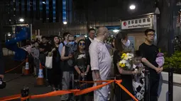 Para penggemar penyanyi dan penulis lagu Coco Lee, berkumpul dengan membawa bunga untuk memberikan penghormatan kepada idola mereka di pemakamannya di Hong Kong pada hari Senin. (AP Photo/Louise Delmotte)