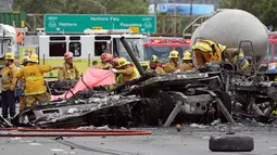 Sejumlah petugas mengevakuasi bangkai truk yang telah hangus usai terjadi tabrakan antara dua truk besar di utara pusat kota Los Angeles (25/4). Kecelakaan ini juga membuat kemacetan panjang di wilayah tersebut. (AP Photo/Reed Saxon)