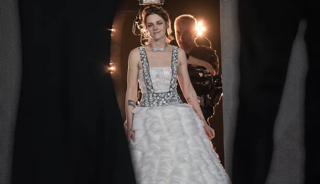Kristen Stewart berjalan di atas panggung saat upacara pembukaan Festival Film Internasional Berlin 'Berlinale', di Berlin, Jerman, Kamis (16/2/2023). Gaun putih Kristen Stewart menampilkan rok mengembang dengan lapisan ruffles, korset putih yang dibordir dan ikat pinggang abu-abu yang dilapisi bunga putih yang memanjang hingga tali bahu. (AP Photo/Markus Schreiber)