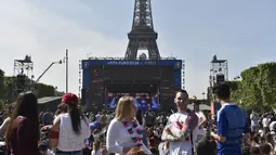 Sejumlah warga berkumpul di sekitar layar raksasa yang terdapat pada acara Champs de Mars yang digelar untuk menyambut Piala Eropa 2016 di Paris fan zone, belakang Menara Eiffel, Prancis, Jumat (10/6/2016). (AFP/Alain Jocard)
