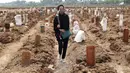 Seorang wanita berjalan di antara kuburan korban COVID-19 di TPU Rorotan, Jakarta, Rabu (7/7/2021). Di seluruh negeri, virus corona COVID-19 kembali menyebar dengan cepat dengan meledak di luar kapasitas dan pasokan oksigen habis. (AP Photo/Tatan Syuflana)